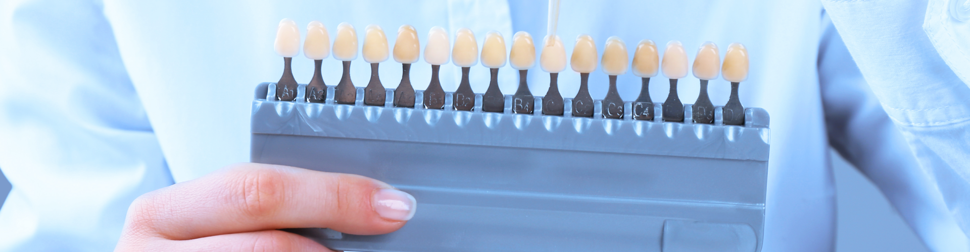 Hand holding tooth shade-matching tool.